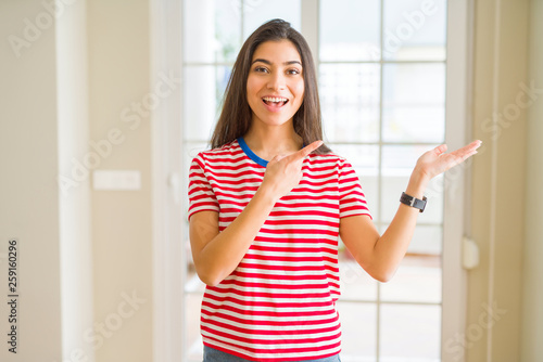 Young beautiful woman wearing casual t-shirt amazed and smiling to the camera while presenting with hand and pointing with finger.