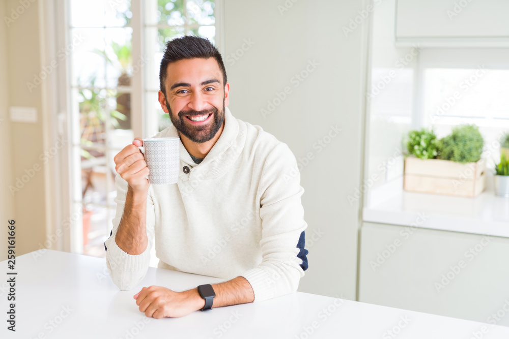 Handsome man smiling while enjoying drinking a cup of coffee in the morning Handsome man smiling while enjoying drinking a cup of coffee in the morning
