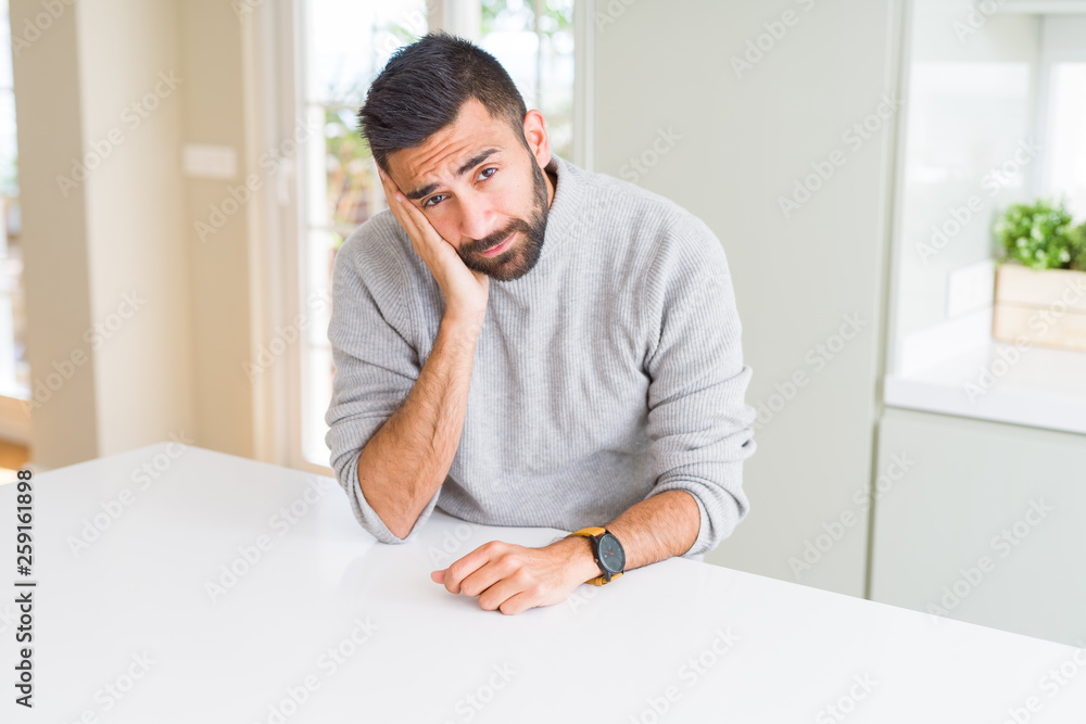 Handsome hispanic man wearing casual sweater at home thinking looking tired and bored with depression problems with crossed arms.