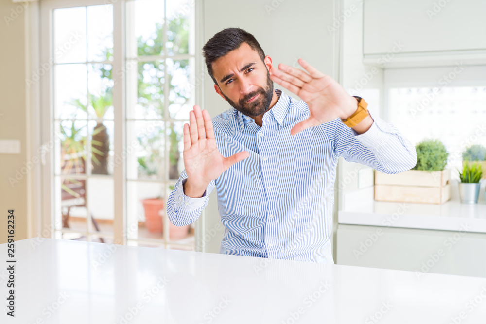 Handsome hispanic business man Smiling doing frame using hands palms and fingers, camera perspective