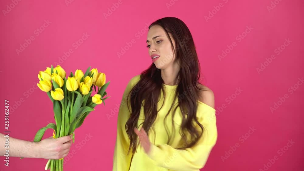 studio shoot of beautiful dissatisfied young woman refusing taking gift box and bouquet of yellow tulips studio shoot of beautiful dissatisfied young woman refusing taking gift box and bouquet of yellow tulips