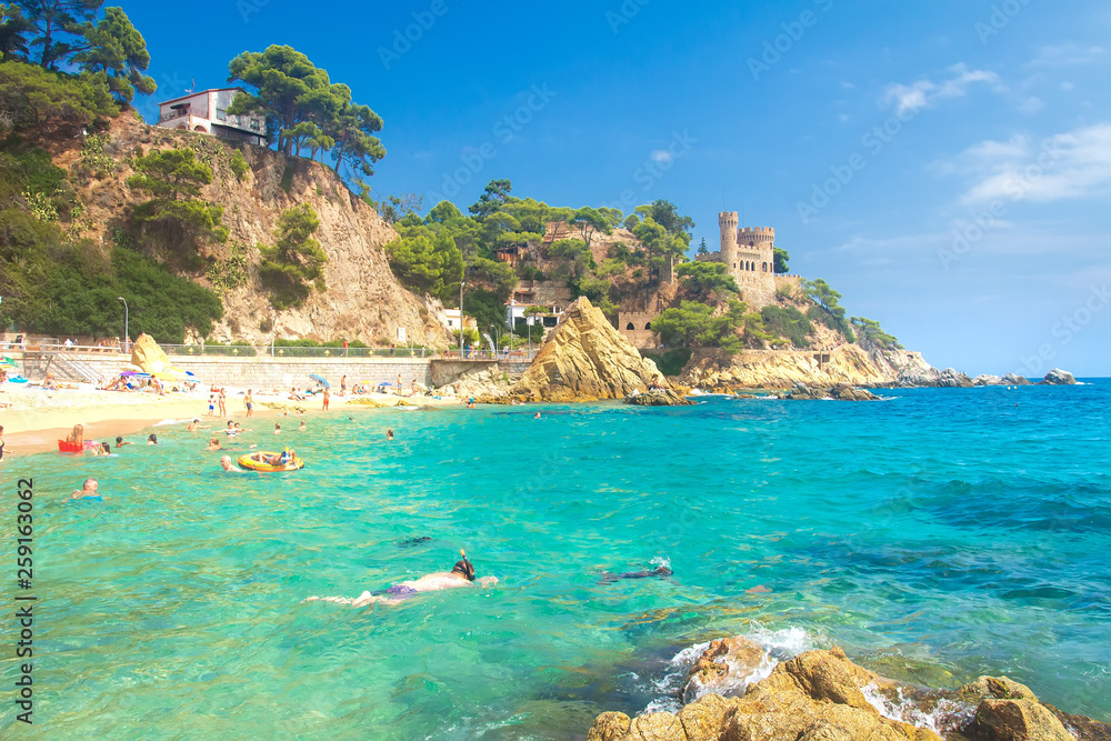 Lloret de Mar beach on sunny summer day with swimming tourists in turquoise sea water, Costa Brava, Spain