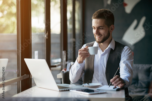 Young man drawing template for the web site associated with digital marketing, current trends and tendencies of UX / UI design. Businessman who rules his company remotely, like a freelancer