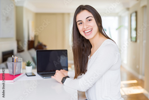 Young beautiful woman smiling using computer laptop with a blank screen on the background