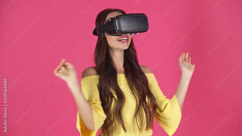 studio shoot of excited young woman in virtual reality headset gesturing isolated on crimson studio shoot of excited young woman in virtual reality headset gesturing isolated on crimson
