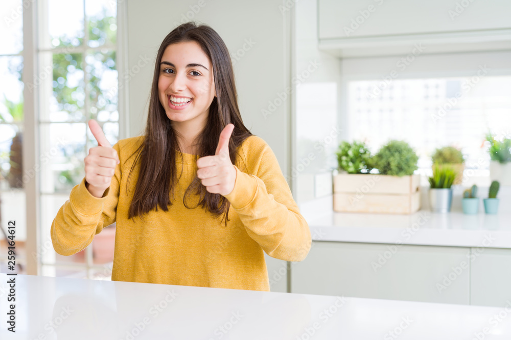 Beautiful young woman wearing yellow sweater success sign doing positive gesture with hand, thumbs up smiling and happy. Looking at the camera with cheerful expression, winner gesture. Beautiful young woman wearing yellow sweater success sign doing positive gesture with hand, thumbs up smiling and happy. Looking at the camera with cheerful expression, winner gesture.