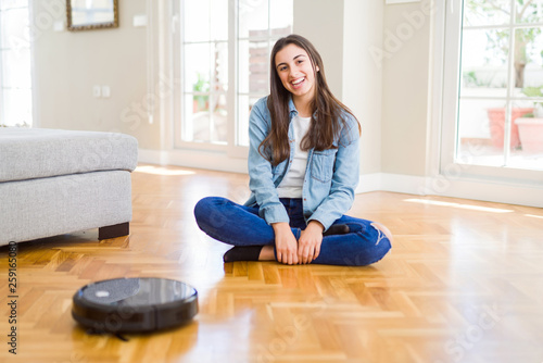 Young woman using automatic vacuum cleaner to clean the floor, controling machine housework robot © Krakenimages.com