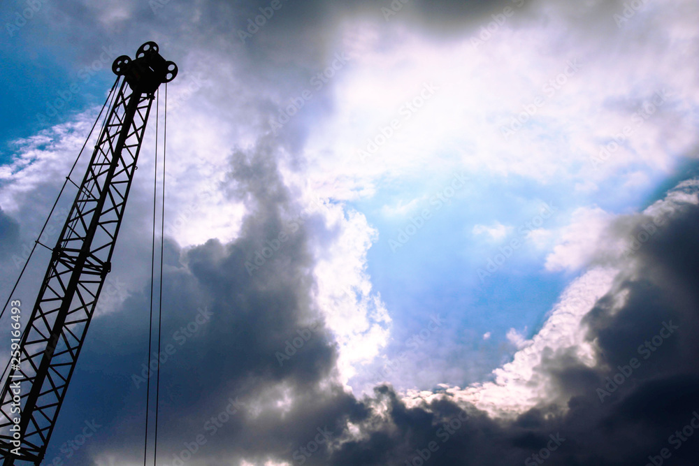 Silhouette of crane against cloudy sky with glimpses of the sun. Copy space. Background. Silhouette of crane against cloudy sky with glimpses of the sun. Copy space. Background.