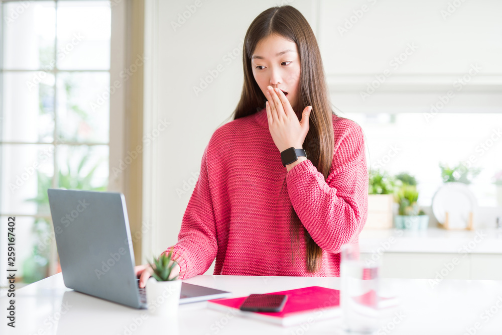 Beautiful Asian woman working using computer laptop cover mouth with hand shocked with shame for mistake, expression of fear, scared in silence, secret concept Beautiful Asian woman working using computer laptop cover mouth with hand shocked with shame for mistake, expression of fear, scared in silence, secret concept