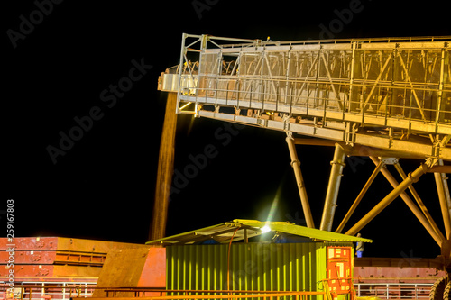A conveyor transports bauxite, which is refined into aluminum, from an storage area into a capesize bulk carrier ship at a river bank jetee at night in the Kamsar, Guinea, West Africa. photo