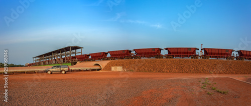 A freight train carrying bauxite in railway carriages for transhipment into a capesize bulk carrier ships by covered conveyor belt mechanism in the Kamsar, Guinea, Africa. photo