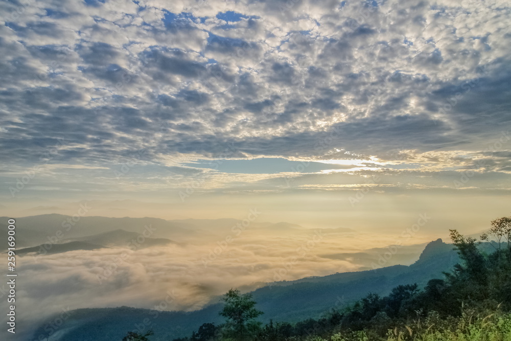 Mountain view morning of the hills around with sea of mist and soft yellow sun light with cloudy sky background, sunrise at Doi Samur Dao, Sri Nan National Park, Nan, Thailand.