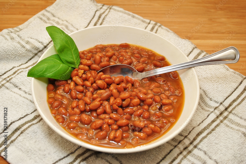 Baked Beans & Bacon Pieces Served in a White Bowl and Garnished with Fresh Basil Baked Beans & Bacon Pieces Served in a White Bowl and Garnished with Fresh Basil