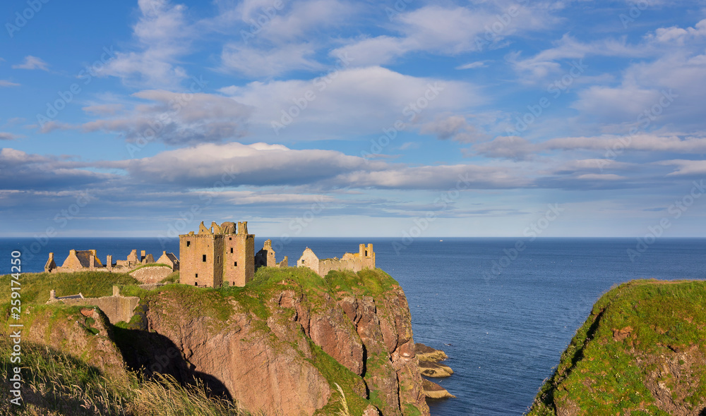 Landscape of Dunnottar Castle ruins withh dark clouds and ocean
