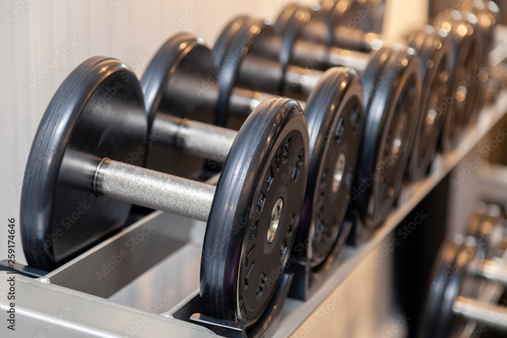 Closeup oshiny metal dumbbells, barbells, weights on the stand in modern gym of hotel. Сoncept of healthy lifestyle, weight loss, training, bodybuilding, bodyfitness, diet, sport exercises Closeup oshiny metal dumbbells, barbells, weights on the stand in modern gym of hotel. Сoncept of healthy lifestyle, weight loss, training, bodybuilding, bodyfitness, diet, sport exercises