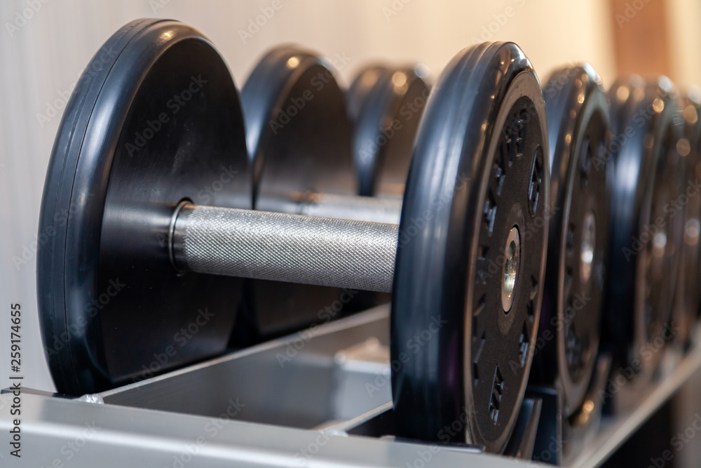 Closeup oshiny metal dumbbells, barbells, weights on the stand in