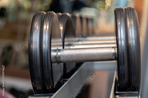Closeup oshiny metal dumbbells, barbells, weights on the stand in modern gym of hotel. Сoncept of healthy lifestyle, weight loss, training, bodybuilding, bodyfitness, diet, sport exercises