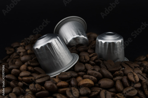 Italian coffee capsules or coffee pods on coffee beans, black background.