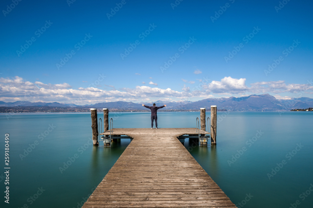 Man standing on a jetty by tranquil lake