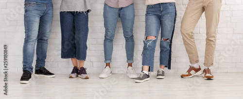 Schilderij op canvas Legs of friends. Young people in jeans and trousers