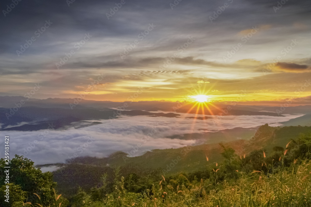 Obraz premium Mountain view morning of the hills around with sea of mist and soft yellow sun light in the sky background, sunrise at Doi Samur Dao, Sri Nan National Park, Nan, Thailand.