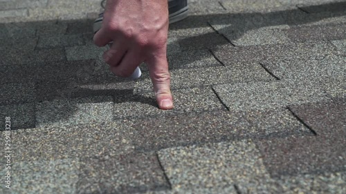 Insurance agent marking roof hail damage with chalk on shingles