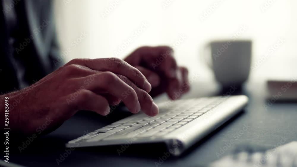 A midsection of businessman with computer sitting at the desk, working. A midsection of businessman with computer sitting at the desk, working.