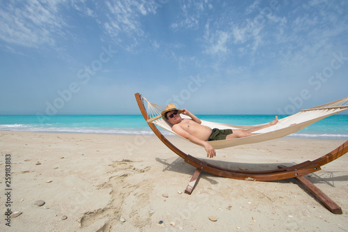 man lying on a hammock resting on the beach