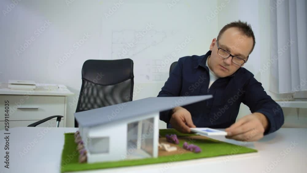 Architect adjusting poolside at a model house in office Architect adjusting poolside at a model house in office