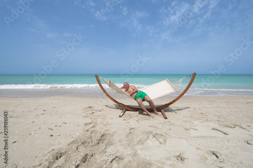 man lying on a hammock resting on the beach