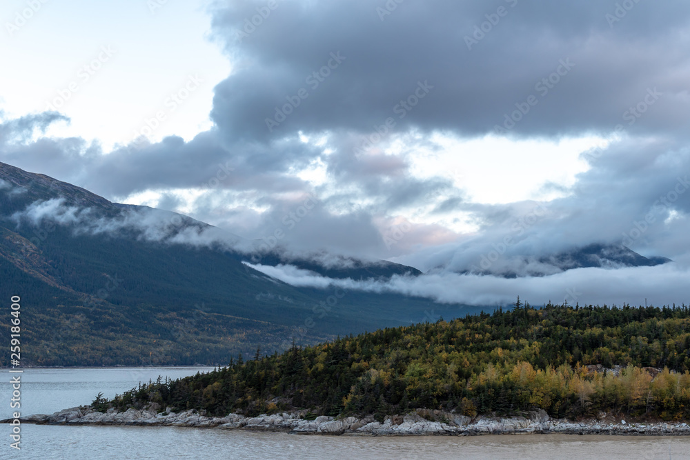 Tranquil scenic mountain and sea landscape in Alaska with low clouds hovering