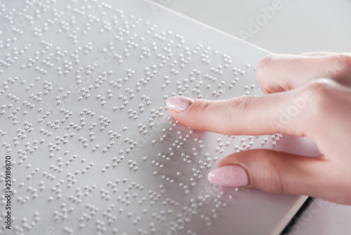 Obraz na płótnie partial view of young woman reading braille text on white paper