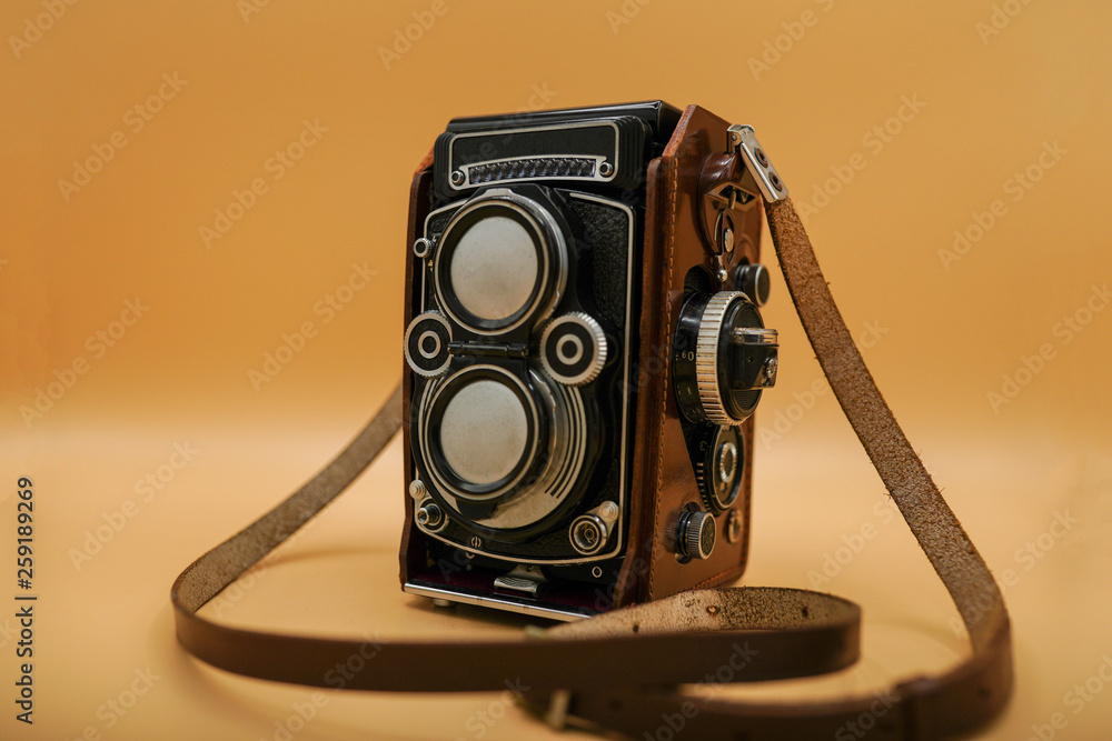 Beautiful old-fashioned medium size camera inside leather box on an orange background. Retro style camera of german design. Antique technology