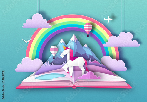 Open fairy tale book with unicorn, rainbow and mountain landscape. Cut out paper art style design