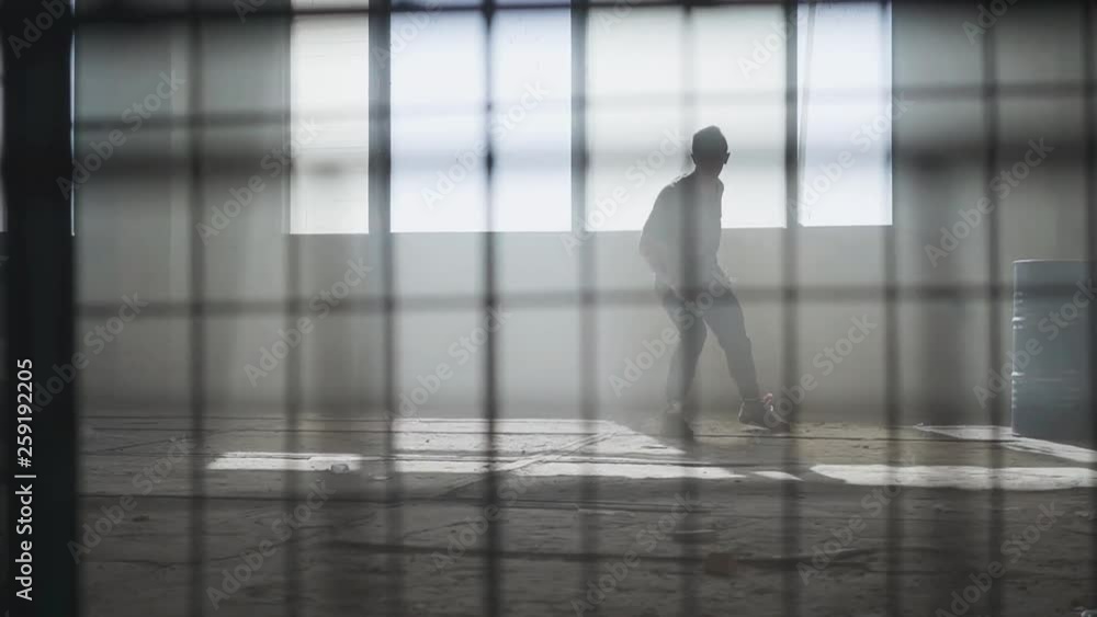 Young street hip-hop dancer performing in front of large window in abandoned building. Contemporary. Hip hop culture. Rehearsal. Slow motion. Young street hip-hop dancer performing in front of large window in abandoned building. Contemporary. Hip hop culture. Rehearsal. Slow motion.
