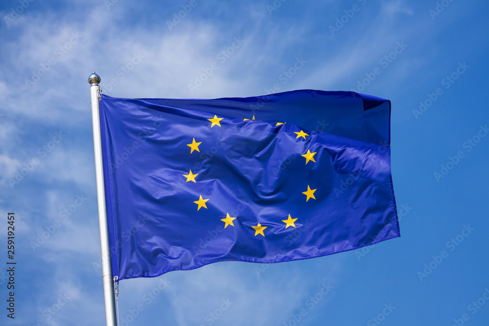 Flag of the European Union waving in the wind on flagpole against the sky with clouds on sunny day, close-up Flag of the European Union waving in the wind on flagpole against the sky with clouds on sunny day, close-up