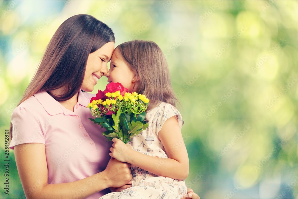 Fototapeta premium Portrait of happy mother and daughter holding flowers