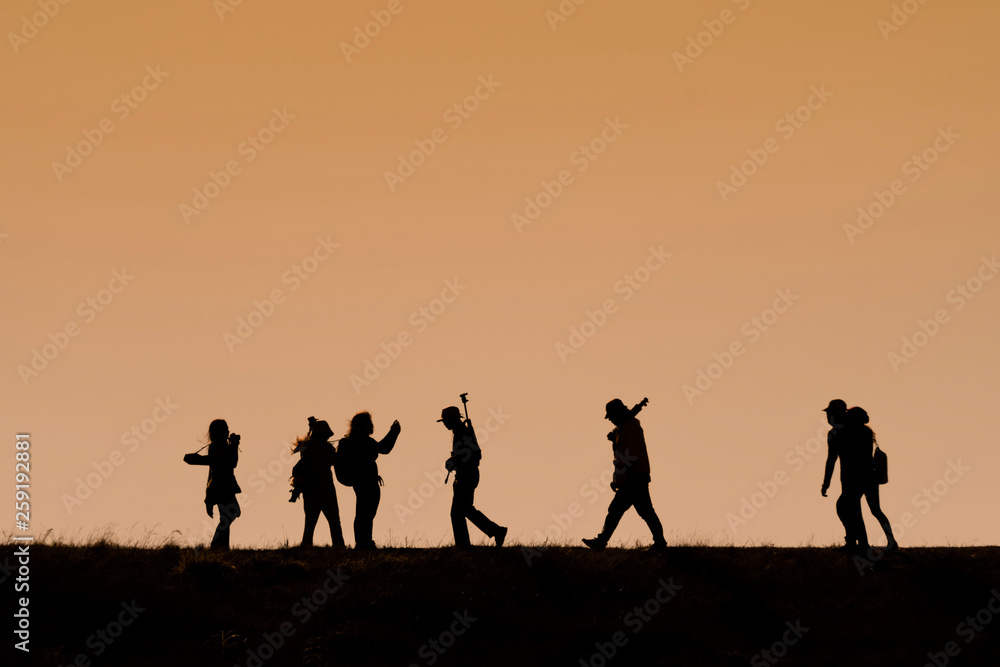 Silhouettes of hikers with backpacks enjoying sunset view from top of a mountain Silhouettes of hikers with backpacks enjoying sunset view from top of a mountain