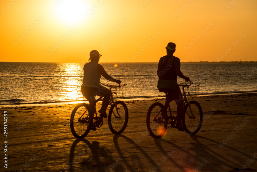 Fototapeta premium Silhouettes of people on an orange beach at sunset.