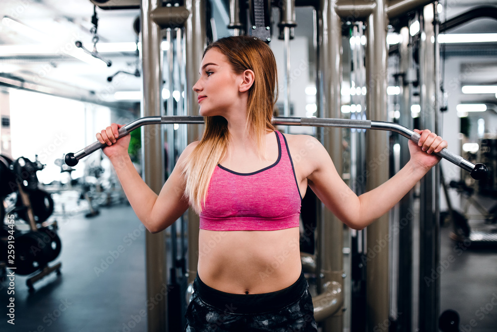 A front view of young girl or woman doing strength workout in a gym.