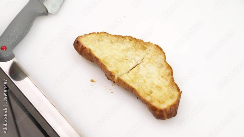 A chef in the professional restaurant kitchen in black gloves cutting roasted croissant into half A chef in the professional restaurant kitchen in black gloves cutting roasted croissant into half