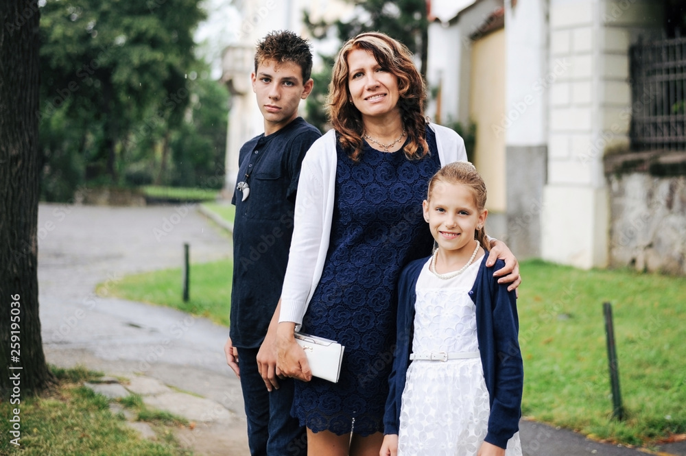 Beautiful woman with two children, son and daughter walking in the park after the rain and breathing fresh air Beautiful woman with two children, son and daughter walking in the park after the rain and breathing fresh air