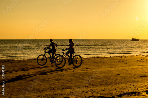 Silhouettes of people on an orange beach at sunset. © bettys4240