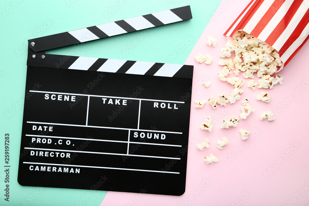 Clapper board with popcorn on colorful background