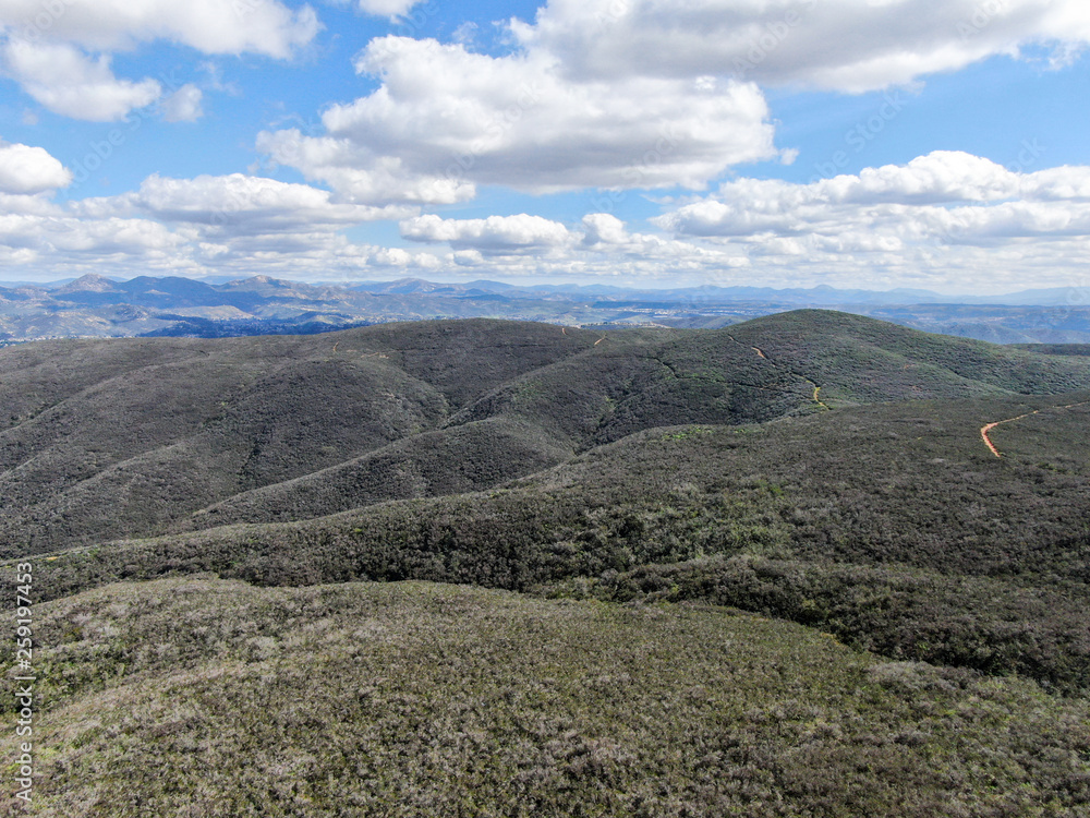 Obraz premium Aerial view of Black Mountain in Carmel Valley, San Diego, California, USA. Green dry mountain during sunny cloudy day with hiking trails, perfect for sport activity an leisure time..