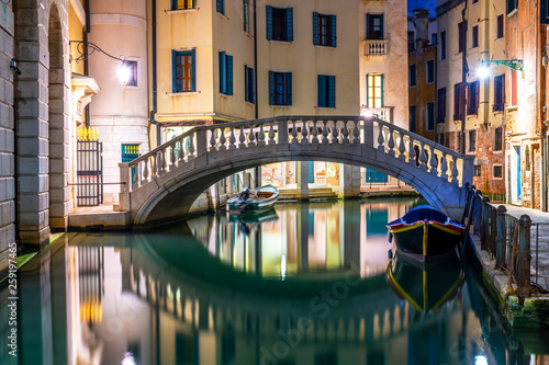 Canal in Venice at night with moored gondolas, Italy