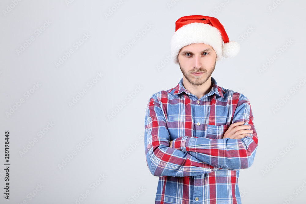 Young man in santa hat on grey background
