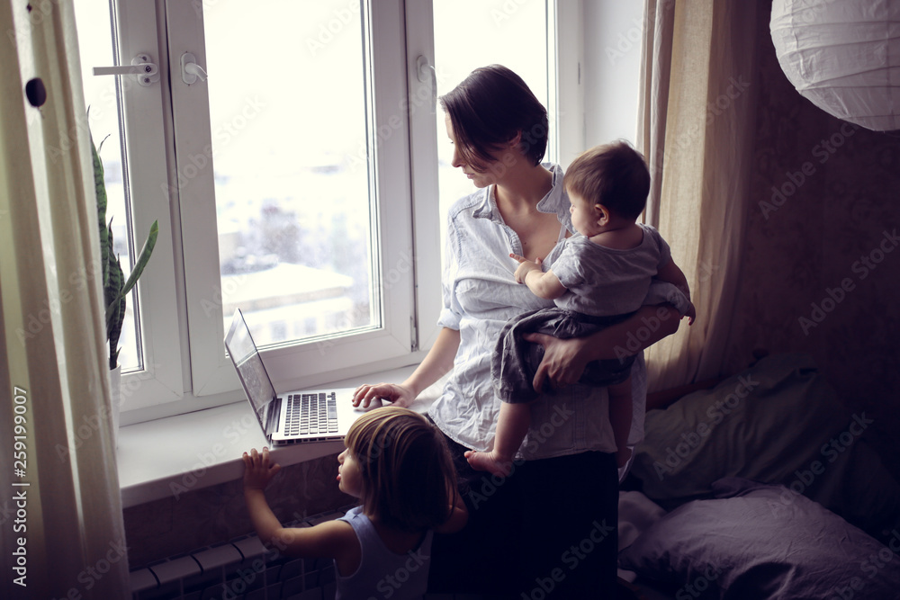 Mom with children working on laptop near window Mom with children working on laptop near window