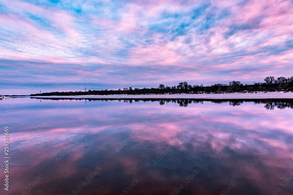 Beautiful reflection of the sky at sunset in the water on the river. Spring background.