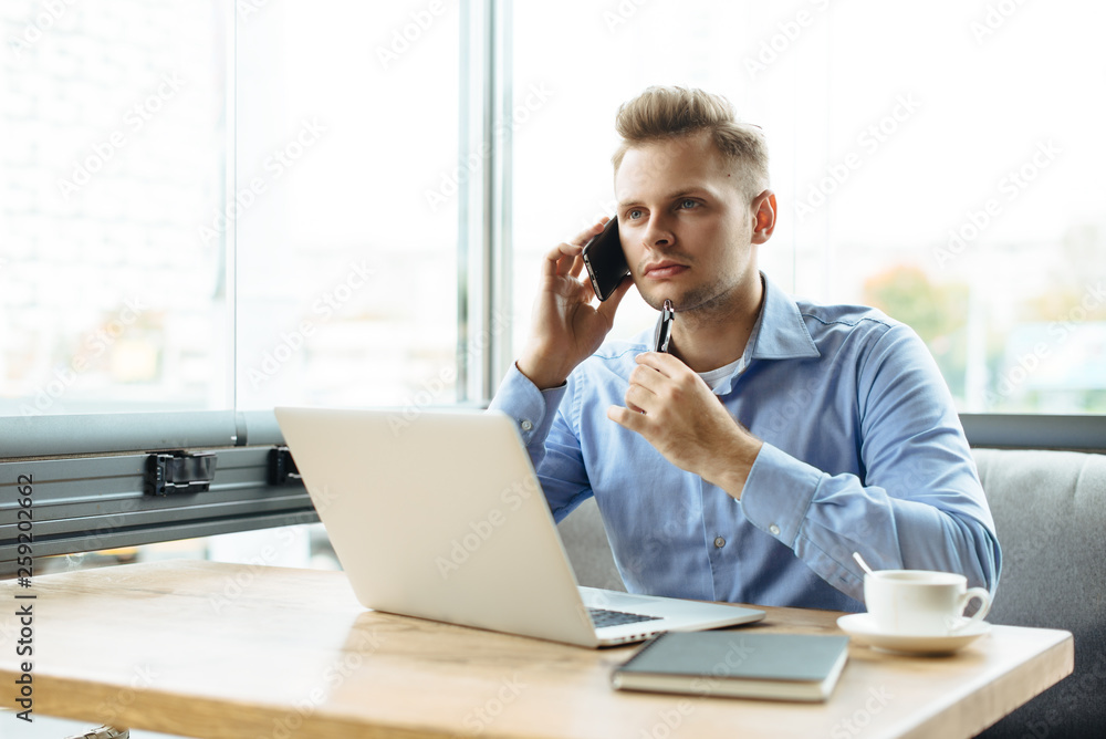 Stylish young man calling by the phone to solve business problems. Online consultation by phone. Freelancer discussing the development and planning of his online project. Outsourcing. Mobile services. Stylish young man calling by the phone to solve business problems. Online consultation by phone. Freelancer discussing the development and planning of his online project. Outsourcing. Mobile services.